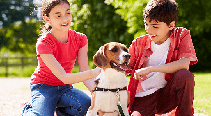 Two kids outside with their pet beagle